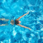 A photo of a woman swimming in a pool taken from above.