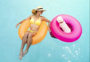 a woman swims in her pool with her pet dog