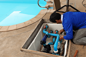 A man beside a pool looking down at pool pipes.