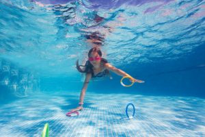 Child grabbing rings from the bottom of a swimming pool