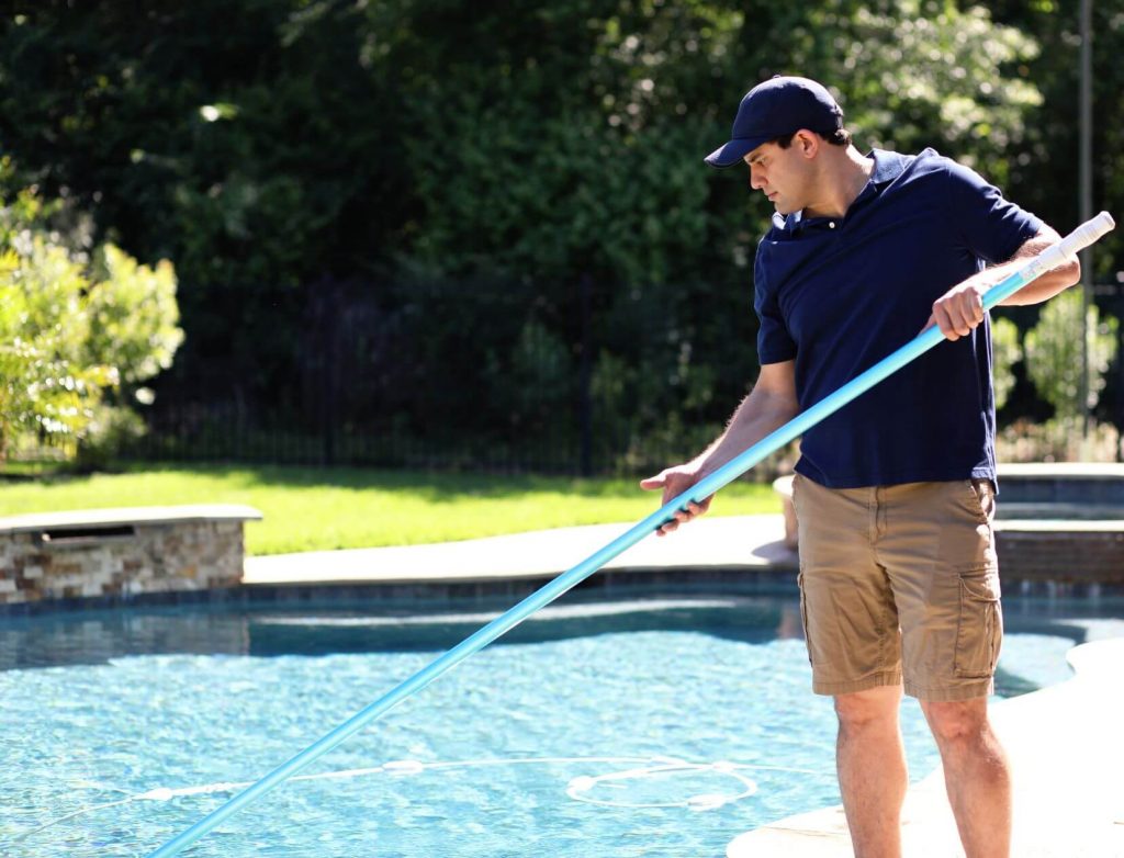 A man skimming a pool