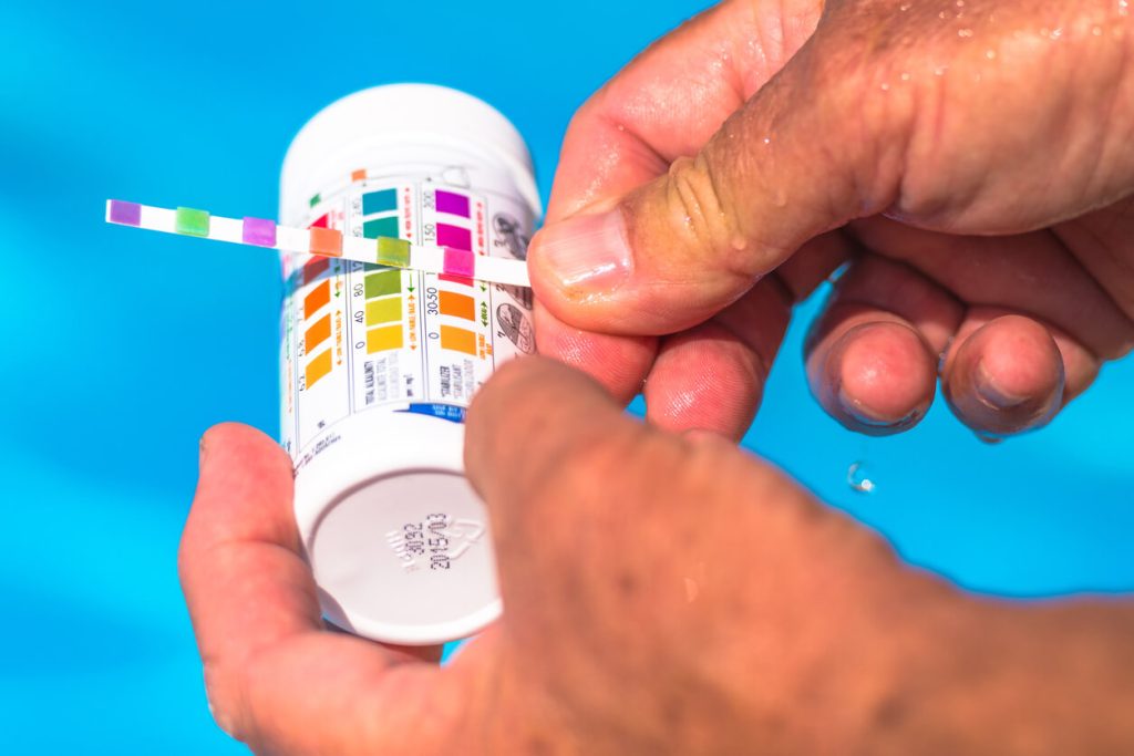 Person testing pool water with a testing strip