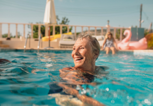 An older woman smiles while she treads water in a pool.