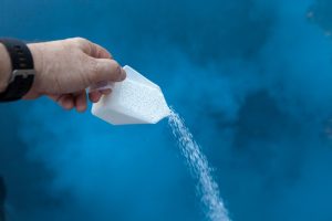 A photo of a hand pouring pool chlorine granules into a pool. 