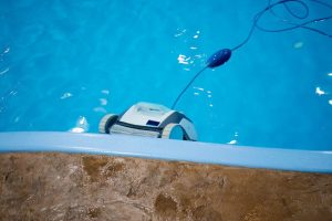 A photo of a robot pool cleaner at the edge of a pool.